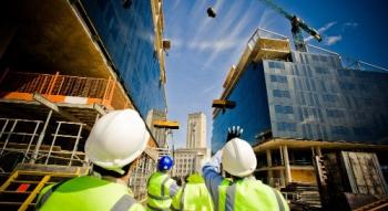 construction workers looking up at a crane